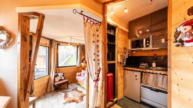 A cozy cabin interior with a wooden interior, a kitchen area with modern appliances, and a view of a snowy landscape through the window. - Immodreams - La Grange - Avoriaz (Avoriaz)