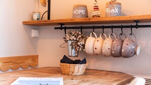 A kitchen counter with a basket of fresh flowers, a magazine, and a hanging rack with mugs. - Immodreams - La Grange - Avoriaz (Avoriaz)