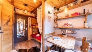 A cozy wooden cabin with a bunk bed, a dining table, and shelves with various items. - Immodreams - La Grange - Avoriaz (Avoriaz)