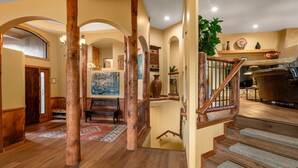 A spacious foyer with a wooden staircase, a large painting, and a wooden bench. - Red Rock Bonanza +Hot Tub, Hikes & Views! (Sedona)