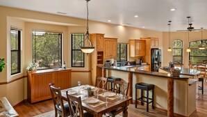 A spacious kitchen with wooden cabinets, a central island, and large windows offering views of the outdoors. - Red Rock Bonanza +Hot Tub, Hikes & Views! (Sedona)