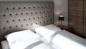 Una cama bien hecha con sábanas blancas y un cabecero capitonado.