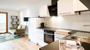 Une cuisine moderne avec des meubles blancs, une cuisinière noire et un plan de travail en bois.