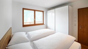 Une chambre avec deux lits, une armoire et une fenêtre.