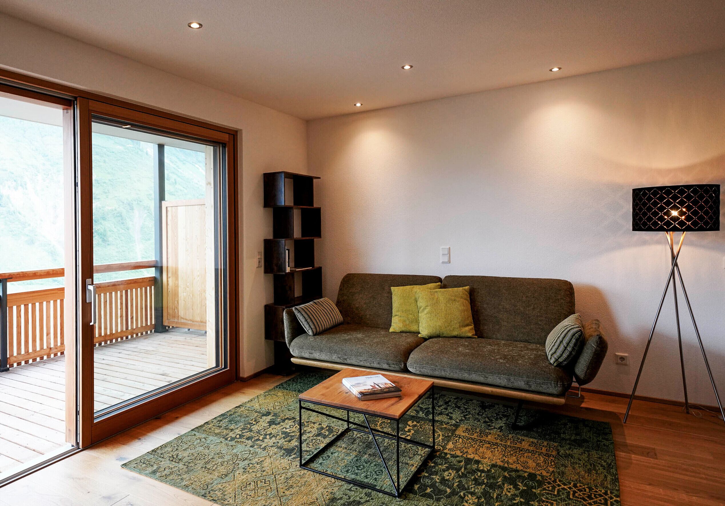 A living room with a sofa, a coffee table, a bookshelf, and a floor lamp.