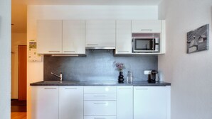 A modern kitchen with white cabinets, a microwave, and a coffee machine.