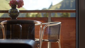 A balcony with wicker chairs and a table, a vase with flowers, and a view of hills. - Hölderle Damüls  - mountain view #11 (Damüls)