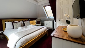 Habitación de hotel con una cama grande, un escritorio, una silla, un televisor y una ventana con cortinas.