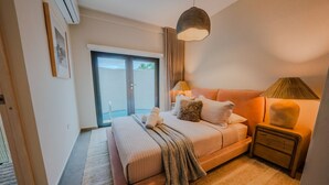 Un dormitorio con cama, mesitas de noche, una lámpara y vistas al exterior.