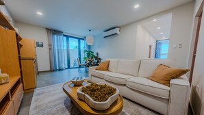 Una sala moderna con un sofá, una mesita de madera y un cuenco decorativo.