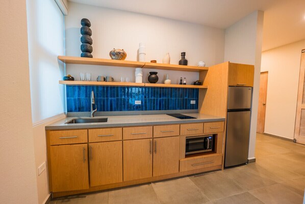 Una cocina moderna con armarios de madera, un refrigerador de acero inoxidable y un salpicadero de azulejos azules.