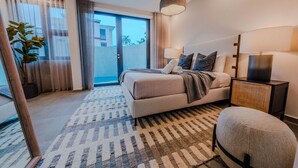 A modern hotel room with a large bed, a side table, a lamp, and a view of the outdoors. - Casa Loba Luxe Unit 3 w/private pool and garden (Rincon)