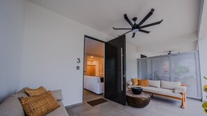 A modern living room with a sofa, a coffee table, and a large window. - Casa Loba Luxe Unit 3 w/private pool and garden (Rincon)