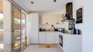 Una cucina moderna con mobili bianchi, forno integrato e macchina da caffè.