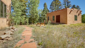 A rustic building with a stone pathway leading to a wooden bench. - Serene Amalia Cabin w/ Deck & Mountain Views (Amalia)
