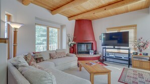 A living room with a sectional sofa, a fireplace, a television, and a wooden ceiling. - Serene Amalia Cabin w/ Deck & Mountain Views (Amalia)