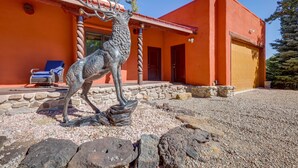 A building with a red exterior, a stone foundation, and a large metal sculpture of a deer. - Amalia Mountain Getaway w/ Deck, Fireplace! (Amalia)