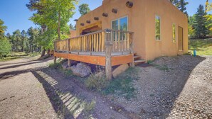 A modern building with a wooden deck and large windows, surrounded by trees and a gravel path. - Charming Amalia Retreat w/ Fireplace & Grill! (Amalia)