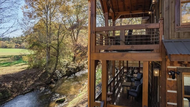 Een houten vakantiehuis met een balkon dat uitkijkt over een rivier en herfstkleuren.
