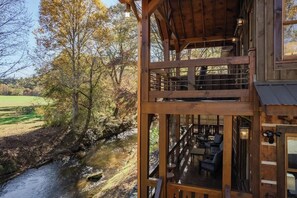 Una cabana de fusta amb un balcó que domina un riu i un paisatge d'ametlles.