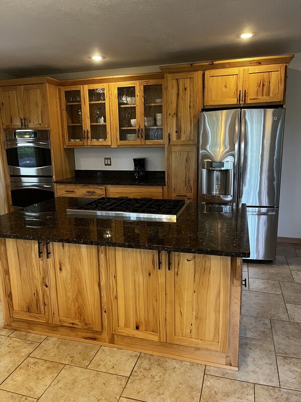 Una cocina con armarios de madera, electrodomésticos de acero inoxidable y encimera de granito.