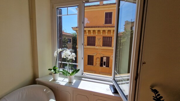 A bathroom with a window, white sink, and two potted plants. - Elegant and spacious suite in upscale setting within walking distance of Villa Borghese. (Roma)