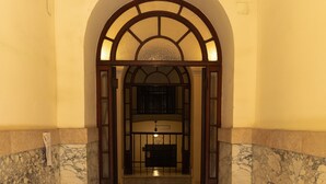 A hallway with a marble floor, an arched doorway, and a tiled floor leading to a room with a desk and chair. - Elegant and spacious suite in upscale setting within walking distance of Villa Borghese. (Roma)
