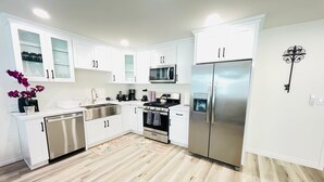 Una cocina moderna con armarios blancos, electrodomésticos de acero inoxidable y piso de madera.