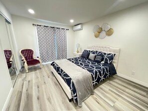 Relax in this stylish bedroom with a large bed, white headboard, and comfortable nightstand.