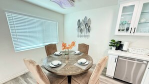 Un comedor con una mesa redonda, sillas acolchadas y un jarrón con flores.