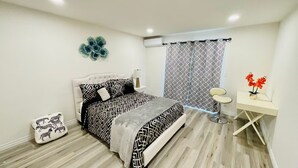 Un dormitorio moderno con cama, mesita de noche, lámpara y un escritorio con silla.