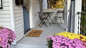 Een veranda met een tafel, stoelen, een deur en een brievenbus.