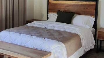 Quarto com cama, um banquinho, uma mesa de cabeceira e uma parede verde.