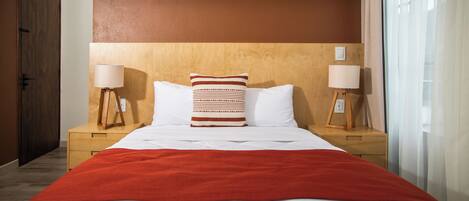 Una habitación de hotel con una cama grande, dos mesitas de noche y un cabecero de madera.