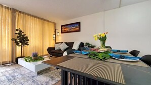 A modern living room with a sofa, coffee table, and dining table set for a meal.