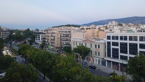 Eine Stadtansicht mit mehrstöckigen Gebäuden, einer Straße mit Fahrzeugen und Bäumen, die die Straßen säumen.