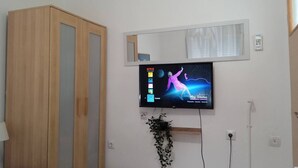 Ein Zimmer mit einem Holzschrank, einem wandmontierten Fernseher mit Netflix-Anzeige und einer Wandklimaanlage.