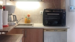 Eine kleine Küche mit Mikrowelle, Kaffeemaschine und Spüle.