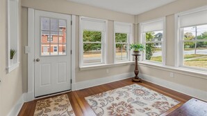 Une pièce avec un plancher en bois, un tapis à motifs et une porte donnant sur l’extérieur.