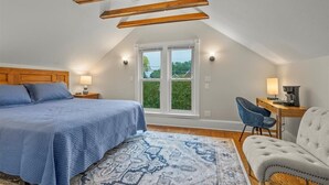 Une chambre à coucher avec un lit, une chaise, un bureau et une fenêtre.
