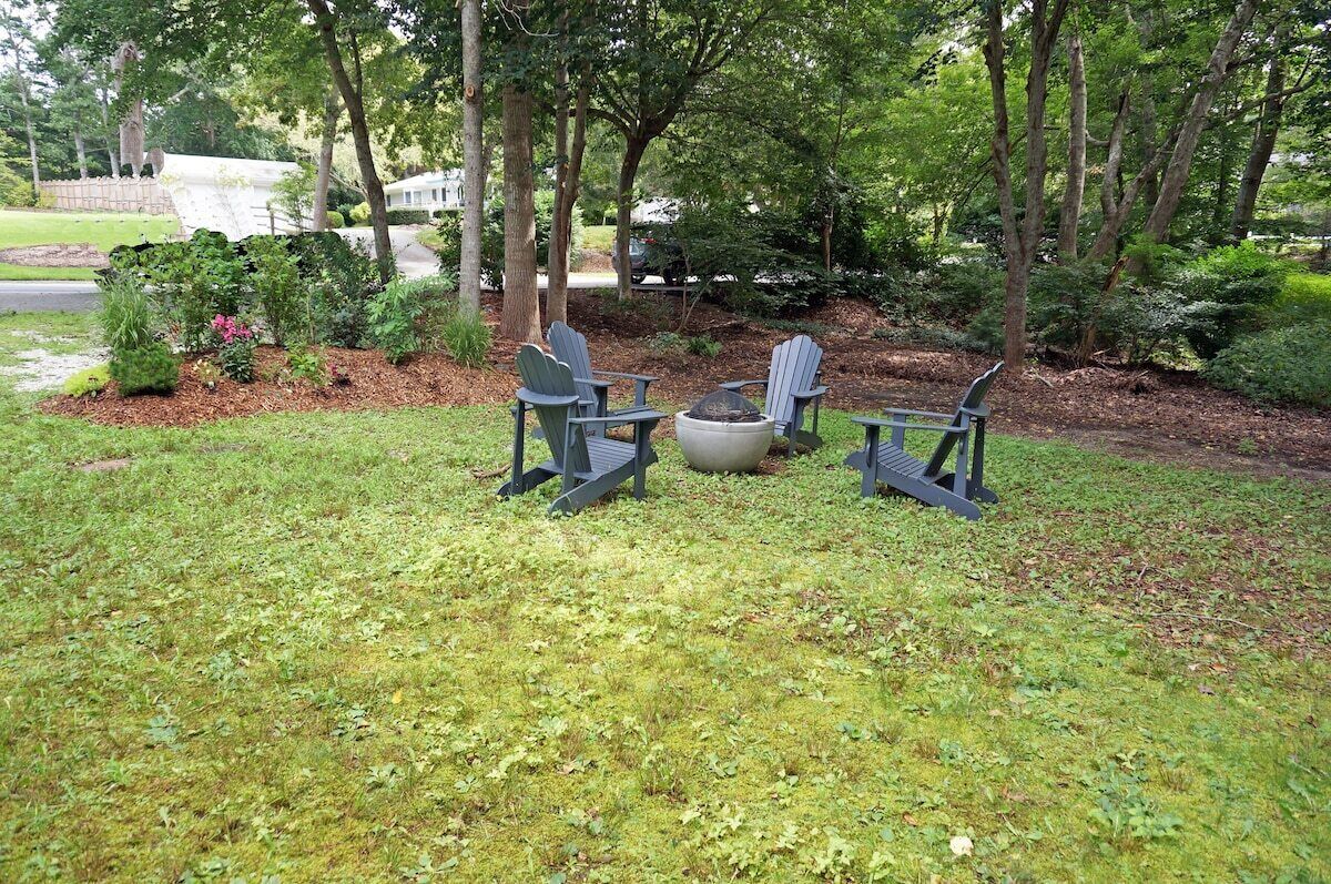 Un espace extérieur aménagé avec des chaises Adirondack et un foyer.