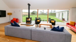 Ein modernes Wohnzimmer mit einem großen grauen Sofa, einem schwarzen Kaminofen und einem roten Sofa.