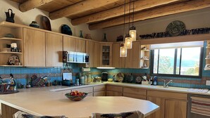 Une cuisine avec des meubles en bois, un grand îlot central et une vue sur l’extérieur.