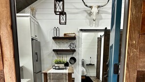 A modern kitchen with wooden flooring, a dining table with a plant centerpiece, and a rustic decor including a cow skull on the wall. - Cabin overlooking lake with great fishing!!!  (Pelahatchie)