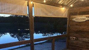 A wooden deck with a patterned rug, a sofa, and a 'WELCOME' sign. - Cabin overlooking lake with great fishing!!!  (Pelahatchie)