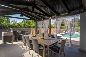 Un patio al aire libre con una mesa, sillas y una piscina.