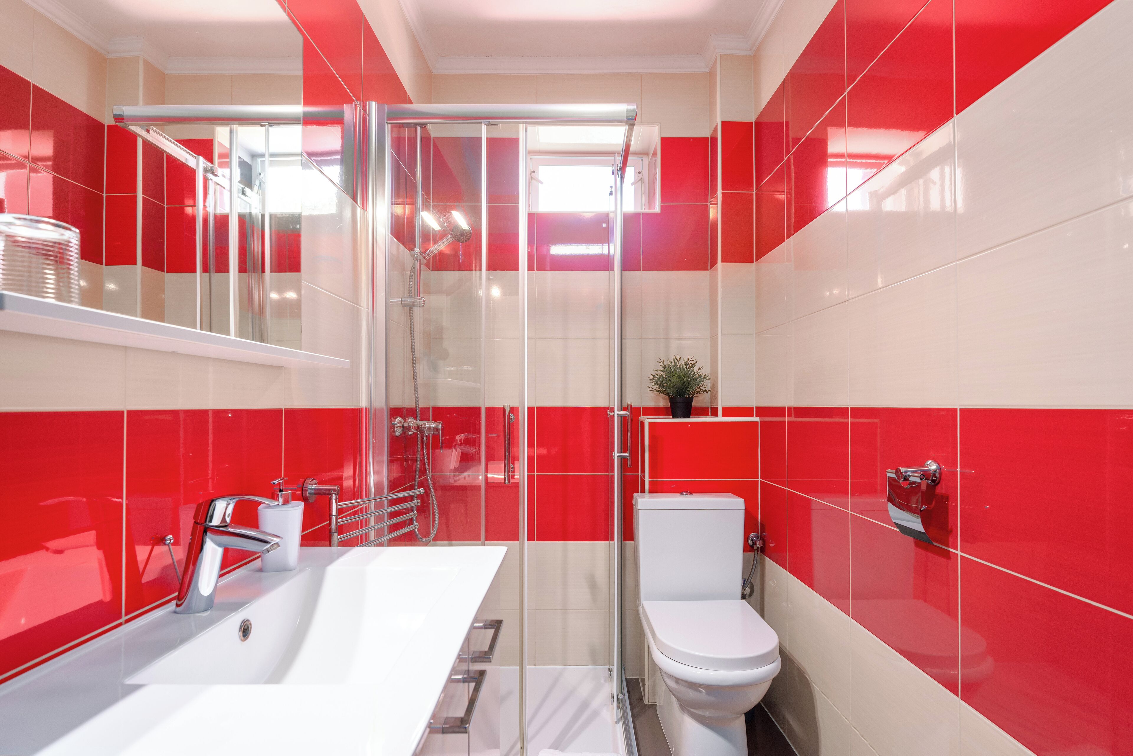 Een moderne badkamer met een douchecabine van glas, een witte wastafel en een toilet.