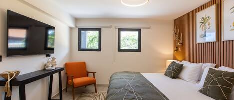 Een moderne hotelkamer met een bed, een bureau, een stoel en een televisie.
