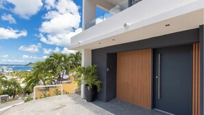 Un bâtiment moderne doté d’une grande porte en bois, d’un balcon et offrant une vue sur la mer.