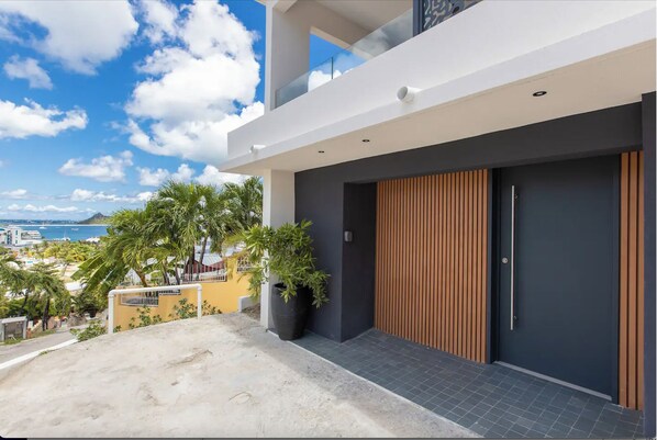 A modern building with a large wooden door, a balcony, and a view of the sea. - Oceanview - 1bedroom  - Walk to beach (Cole Bay)